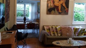 A living room with a sofa, a dining area, and a painting on the wall.