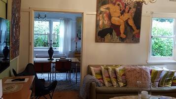 A living room with a sofa, a dining area, and a painting on the wall.