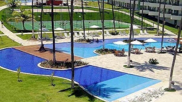 Ein Resort mit großzügigem Poolbereich, Palmen und Blick auf den Ozean.