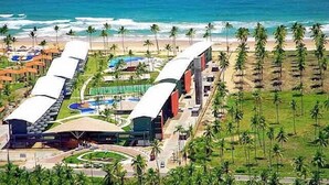 Ein Resort mit Blick auf den Strand, mehreren Schwimmbecken und einem großen Gebäude mit einer gewölbten Dachform.