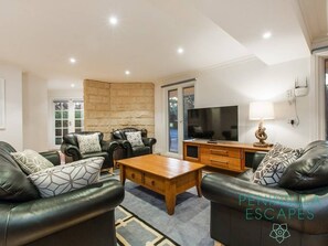 A modern living room with leather sofas, a wooden coffee table, and a stone accent wall.