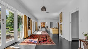 A spacious hallway with a large rug, a sofa, and a dining table.