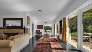 A spacious living room with a fireplace, a large rug, and a view of the outdoors.