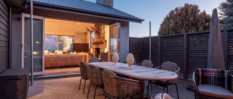 Un patio al aire libre con mesa, sillas y una chimenea.