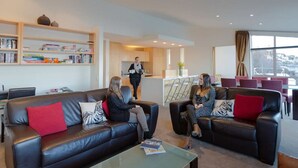 A modern hotel lobby with leather sofas, a coffee table, and a reception area. - Lake View Villa | Great location | Amazing views (Queenstown)