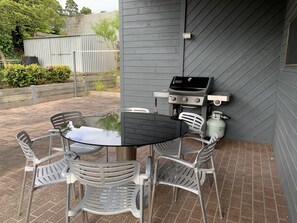 An outdoor patio with a round table and four chairs, a barbecue grill, and a propane tank. - Family Beach Home Dromana -Relax and take in the views of the bay (Dromana)