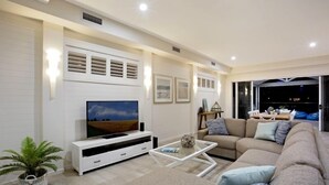 Una sala de estar moderna con televisor de pantalla plana, un sofá, una mesa de centro y una planta en maceta.