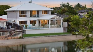 Una casa de dos pisos con piscina, ventanas amplias y vista al agua.