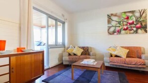A living room with a wooden cabinet, two sofas with cushions, a coffee table, and a painting on the wall.