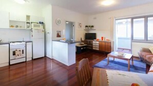 A compact kitchen with a stove, microwave, and refrigerator. There is a dining area with a table and chairs.