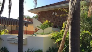 A building with the number 66, surrounded by lush greenery and palm trees.