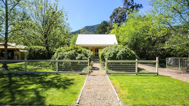 Un bâtiment doté d’un toit en métal, entouré d’un chemin de gravier et d’une clôture en métal.