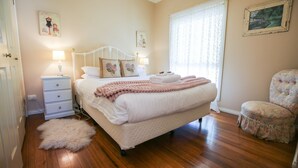 Une chambre à coucher avec un lit, des tables de chevet, une chaise et une fenêtre avec des rideaux.