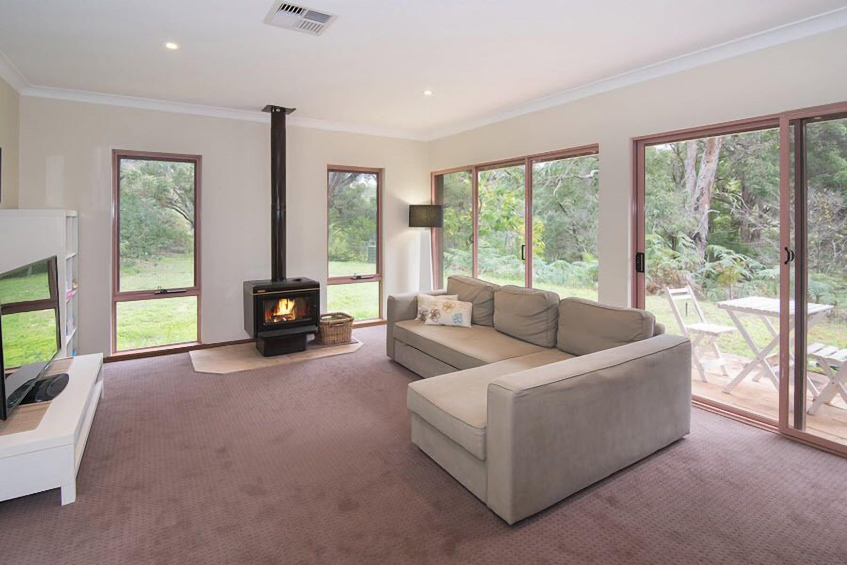 Una sala de estar con sofá, chimenea y grandes puertas corredizas de vidrio que dan a un patio.