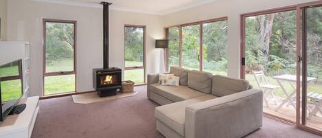 Una sala de estar con sofá, chimenea y grandes puertas corredizas de vidrio que dan a un patio.
