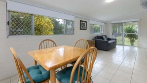 Une pièce spacieuse comprenant une table à manger, des chaises, un canapé et de grandes fenêtres.
