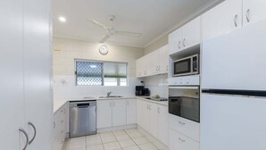 A modern kitchen with white cabinets, a dishwasher, a microwave, and a ceiling fan.