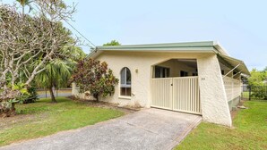A single-story house with a covered porch, a gated entrance, and a paved driveway.