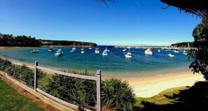 Eine Küstenansicht mit einem Sandstrand und einer Reihe von Booten, die im Wasser vor Anker liegen.