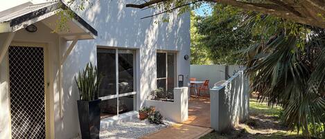A modern house with a covered patio, a small garden, and a pathway leading to the entrance.