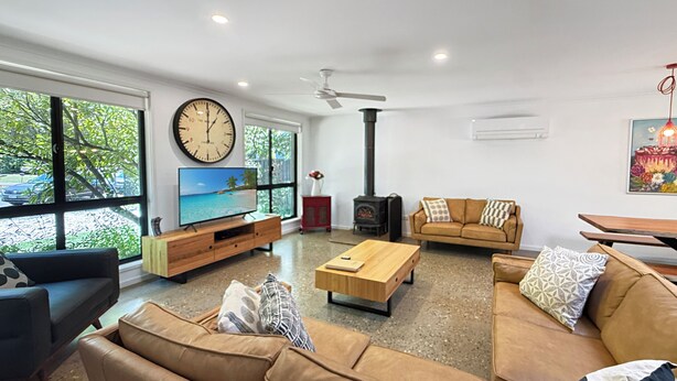 A modern living room with a large window, a television, a fireplace, and a sofa. - ALL NEW Tessies House-150m to river-7 min. walk to town-pets welcome-quiet court (Bright)