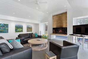 A modern living room with a fireplace, a television, and artwork on the walls.