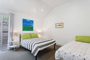 A bedroom with a bed, a bedside table, a lamp, a painting, and a framed picture on the wall.