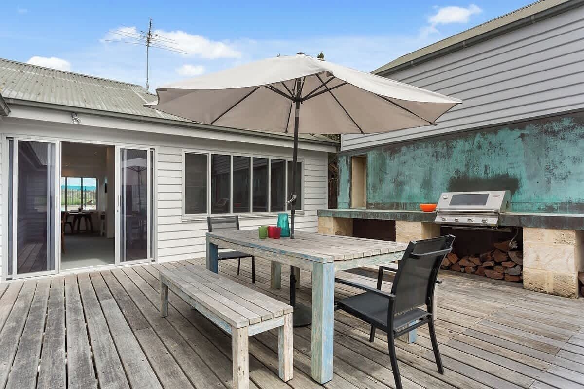 An outdoor patio with a table and chairs, a grill, and a sliding glass door leading to an indoor area.