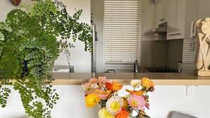 A modern kitchen with white cabinets, a stove, and a window with blinds. - Coastal Calm at Bronte Beachside Escape (Bronte)