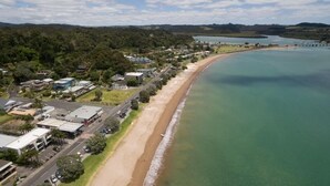 Une vue aérienne d’une ville côtière avec une plage, des maisons et une route.