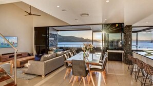 Una sala de estar moderna con comedor, ventanas amplias con vista al mar y una pared de acento de piedra.