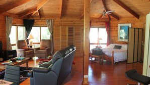 Et hyggeligt sommerhusinteriør med træloft, en sofa, en seng og et spiseområde.