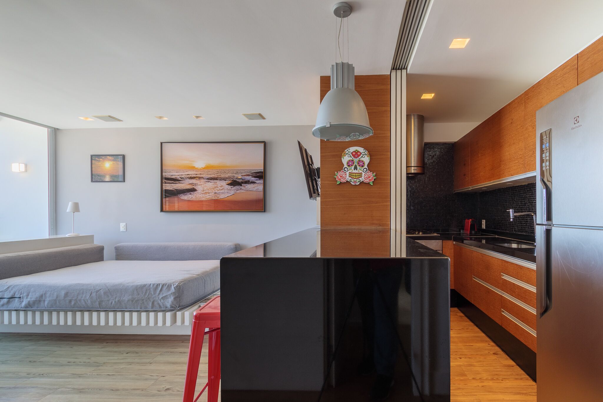 A modern apartment with a bed, kitchenette, and a large window with a view.