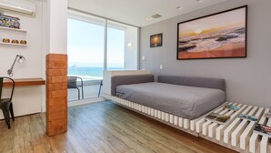 Una habitación moderna con una cama, un escritorio y vista al océano.
