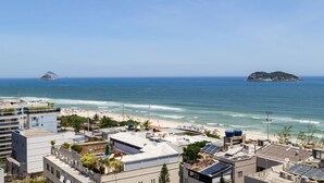 Un paisaje costero con playa, edificios e islas a lo lejos.