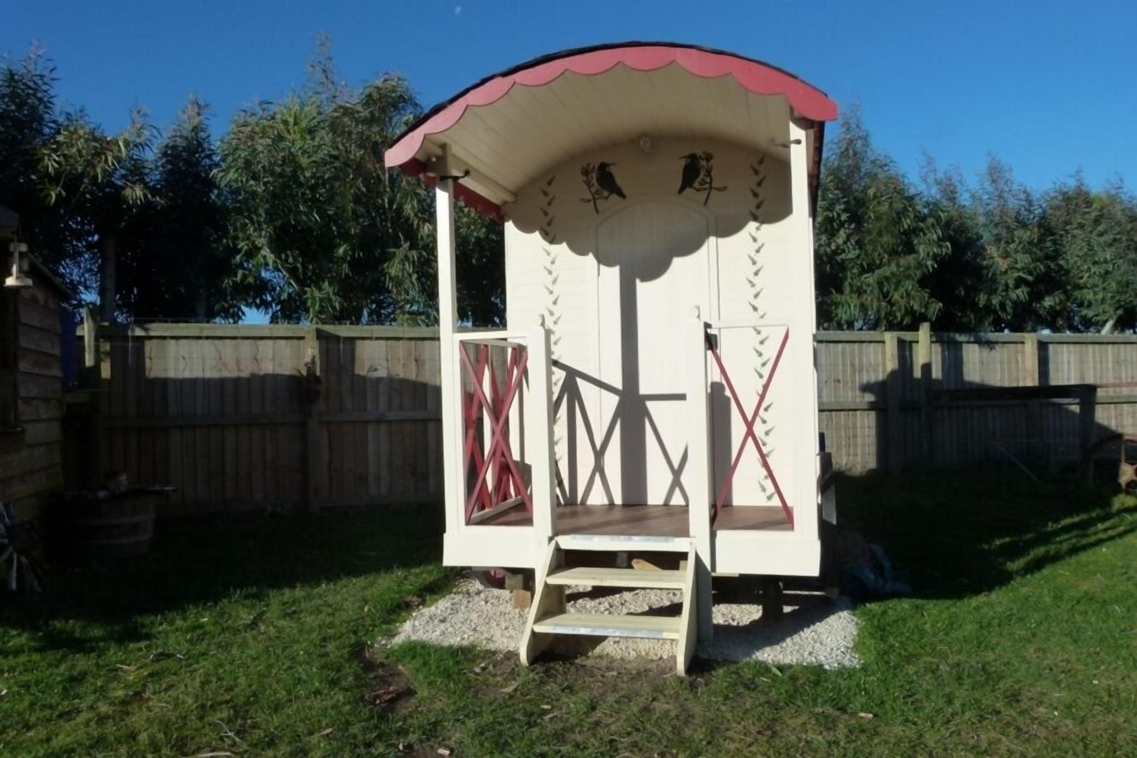 Une petite construction à un seul étage, avec un toit rouge et des murs blancs, et un escalier menant à une porte.
