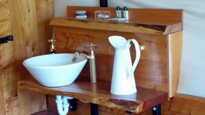 A wooden vanity with a white sink and a white pitcher.