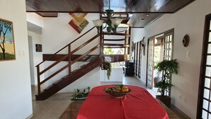 Un couloir décoré d’une nappe rouge, avec un escalier en bois et des plantes en pot.