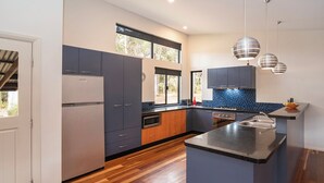 Une cuisine moderne avec des meubles gris, un plancher en bois et un pare-feu bleu.