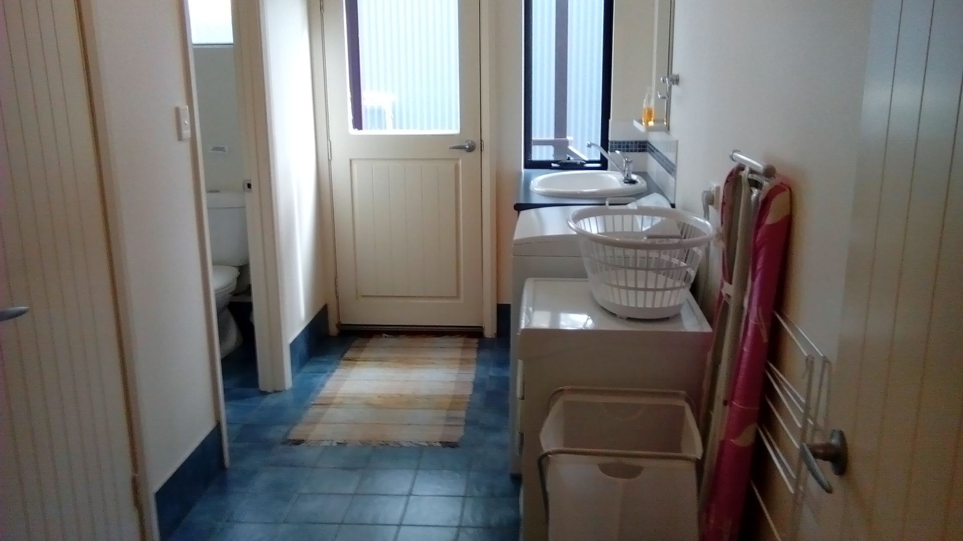 A narrow bathroom with a toilet, a sink, and a shower area.