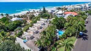A coastal hotel with multiple buildings, a swimming pool, and lush greenery.