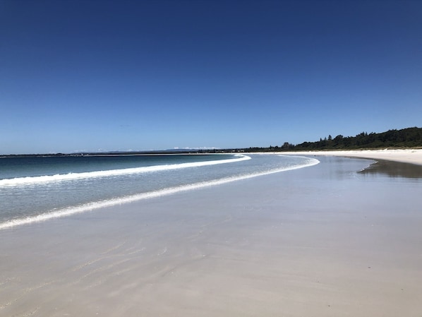 A beach with a clear sky, calm water, and a sandy shore.