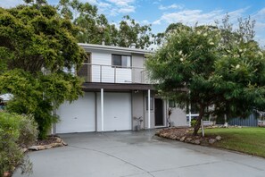A two-story house with a garage, surrounded by trees and a well-maintained lawn.