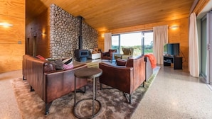 Uma sala de estar moderna com sofás de couro, parede de pedra, lareira e uma janela grande.