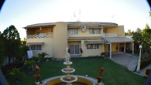 Ein zweistöckiges Gebäude mit Innenhof, Brunnen und überdachter Terrasse.