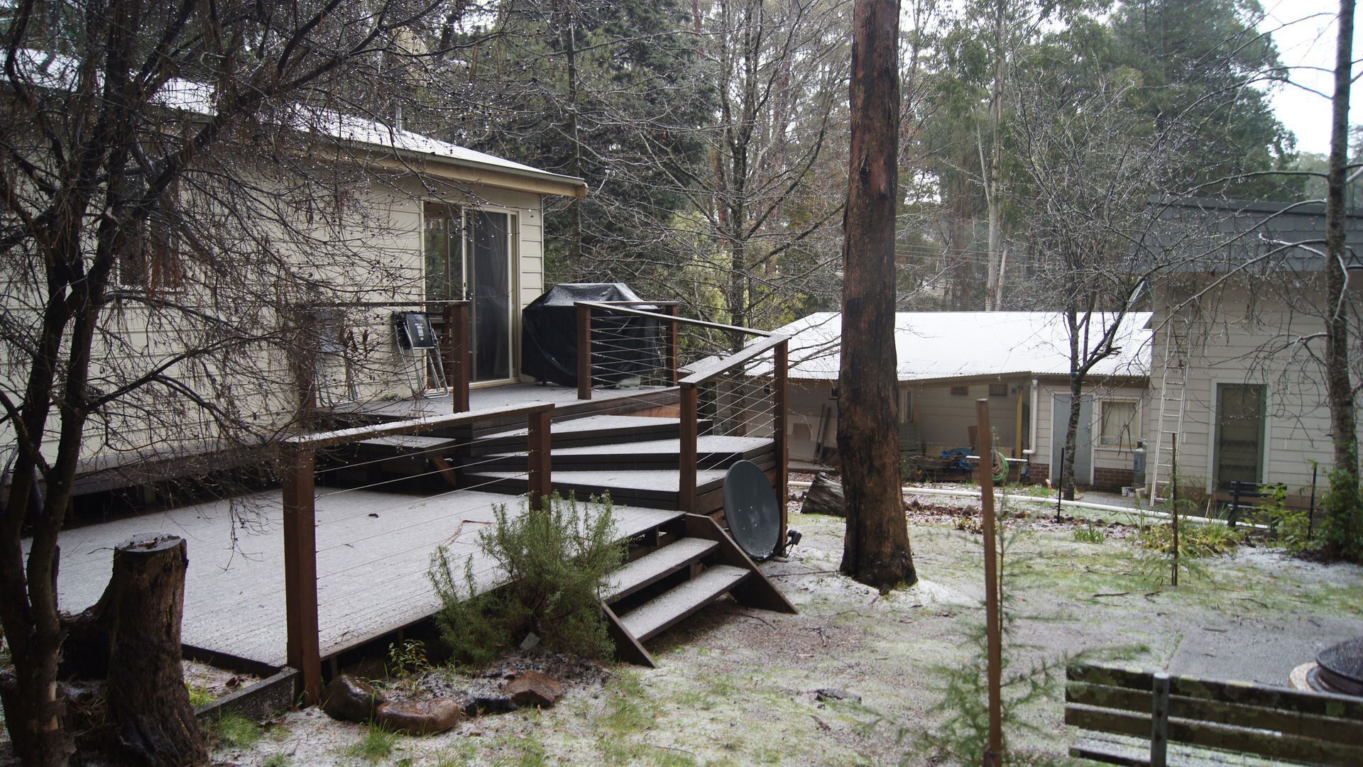 A house with a wooden deck and a staircase leading to a covered area.