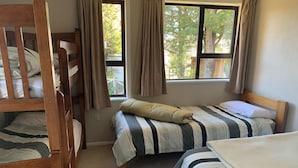 Ein Zimmer mit Etagenbetten, einem Einzelbett und einem Fenster mit Vorhängen.