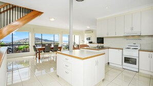 A modern kitchen with white cabinetry, a central island, and a dining area with a view.