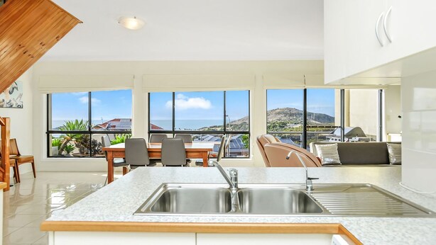 A modern kitchen with a large island, a dining area with a view, and a seating area with a view.