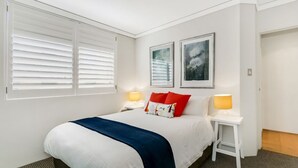 Une chambre à coucher avec un lit, deux lampes de chevet, une table de chevet et deux tableaux encadrés accrochés au mur.